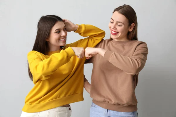 Female Friends Bumping Fists Light Background — Stock Photo, Image