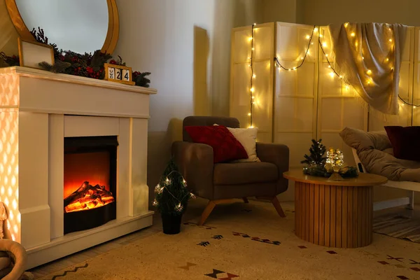 暗いリビングルームのクリスマスの装飾が付いている灰色のアームチェア 暖炉および木のコーヒー テーブル — ストック写真