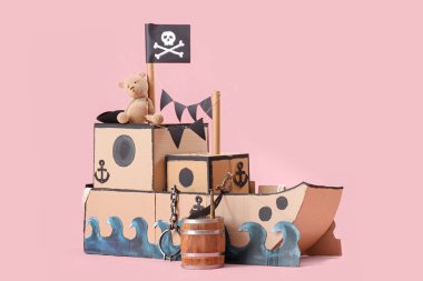 Pembe arka planda oyuncak ayısı olan korsan karton gemi