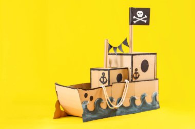 Sarı zemin üzerinde ip olan korsan karton gemi.