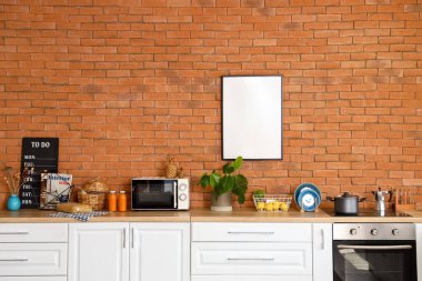 Modern mutfak içi tuğla duvarda boş poster var.