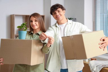 Anahtarı olan ve yeni dairelerinde kutuları taşıyan genç bir çift.
