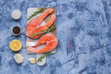 Çiğ somon bifteği ve mavi arka planda farklı baharatlar olan pano.