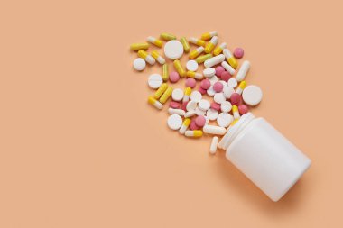 Turuncu arka planda farklı dağıtılmış haplarla dolu kavanoz.