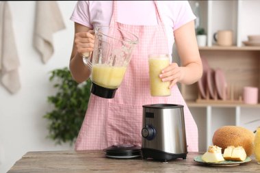 Mutfaktaki masada nefis kavunlu smoothie içen kadın.