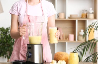 Mutfaktaki masada nefis kavunlu smoothie içen kadın.