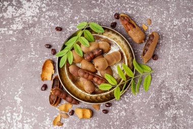 Gri arka planda lezzetli tamarinler, yapraklar ve tohumlar