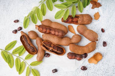 Beyaz arka planda lezzetli tamarindler, yapraklar ve tohumlar