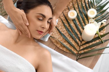 Kaplıca salonunda masaj yaptıran genç bir kadın.