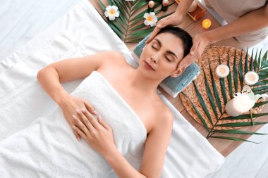 Kaplıca salonunda masaj yaptıran genç bir kadın.