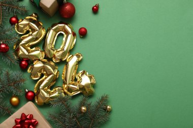 Şekil 2024 hediye kutuları ve yeşil arka planda Noel süsleri olan balonlardan yapılmış.