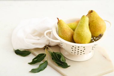 Beyaz zemin üzerinde olgun armutları olan Colander