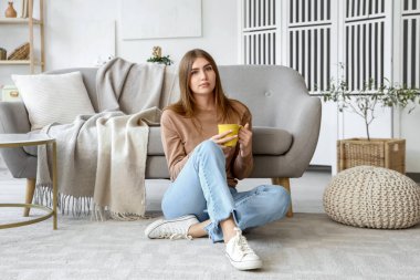 Evde bir fincan sıcak çayla genç bir kadın.