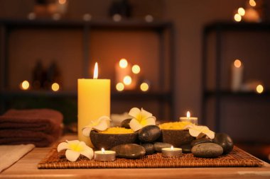 Plumeria çiçekleriyle kaplıca kompozisyonu ve karanlık salonda mum yakma, yakın plan.