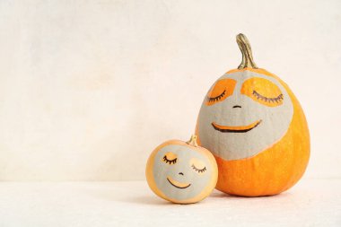 Çizilmiş yüzleri ve açık arkaplanda kil maskeleri olan balkabakları