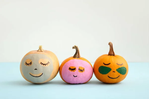 Pumpkins with under-eye patches and masks on blue table