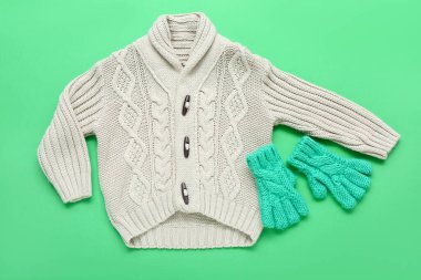 Çocukların ördüğü süveter ve arka planda kalın eldivenler.