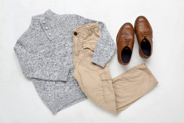 Hafif arka planda şık çocuk süveteri, pantolonu ve ayakkabıları