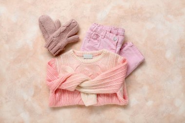 Renkli arka planda çocuk süveteri, pantolonu ve eldivenleri var.