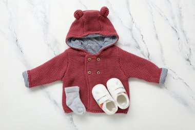 Stylish baby sweater, socks and booties on light background clipart