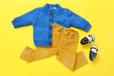 Şık bebek süveteri, sarı arka planda pantolon ve popolar.