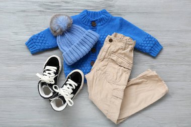 Gri ahşap arka planda şık çocuk kıyafetleri ve ayakkabıları