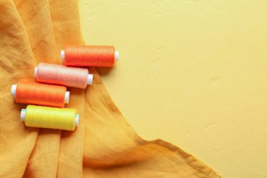 Renk arkaplan üzerinde iplik makaraları ve kumaş kümesi