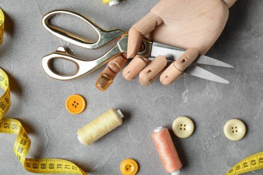 Ahşap elli, makaslı ve grunge arkaplanda dikiş malzemeleri var.