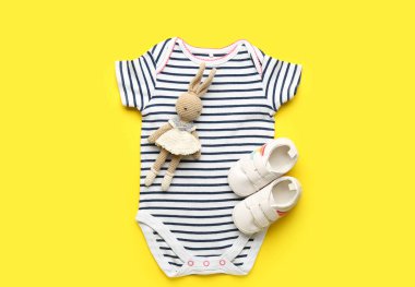 Bebek giysisi, patik ve sarı arka planda örülmüş oyuncak.
