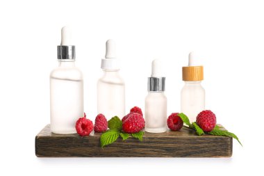 Beyaz arka planda kozmetik ahududu yağı şişeleri olan ahşap tahta tahta.