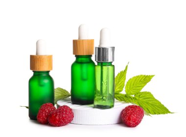 Beyaz arka planda kozmetik ahududu yağı şişeleriyle dekoratif podyum