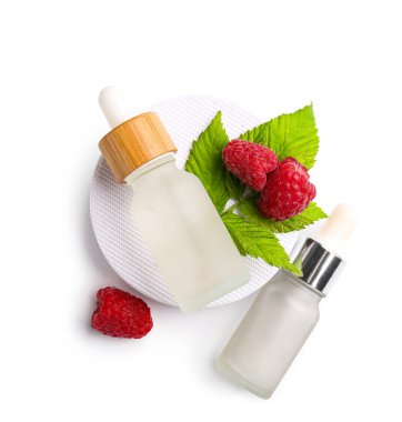 Beyaz arka planda kozmetik ahududu yağı şişeleriyle dekoratif podyum