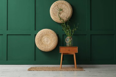 Bambu saplı vazo, renkli duvarın yanındaki ahşap masada.