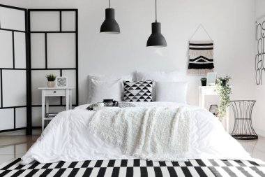 Beyaz battaniyeli rahat yatak ve şık yatak odasının içinde yastıklar.