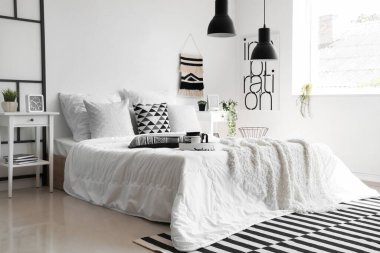 Beyaz battaniyeli rahat yatak ve şık yatak odasının içinde yastıklar.