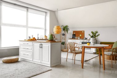 Beyaz tezgahlı ve yemek masalı modern mutfağın içi.