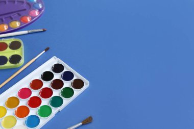 Mavi arkaplanda suluboya boya ve fırça seti