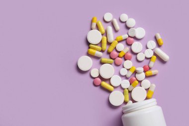 Leylak arka planında farklı dağılmış haplarla dolu kavanoz.