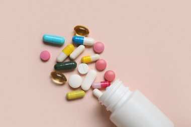 Bej arka planda farklı dağılmış haplarla dolu kavanoz.