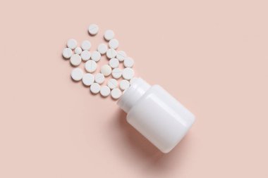 Bej arka planda dağınık haplarla dolu kavanoz.