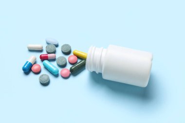 Mavi arka planda farklı dağınık haplarla dolu kavanoz.