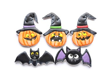 Cadılar Bayramı kutlaması için beyaz arka planda yarasa ve balkabağı şeklinde lezzetli kurabiyeler.