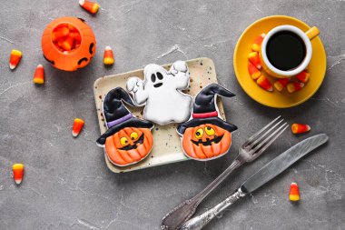 Gri arka planda Cadılar Bayramı kutlaması için lezzetli kurabiyeler, mısır şekeri ve bir fincan kahve.