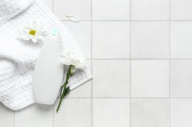 Hafif fayans zemin üzerinde kozmetik ürün, havlu ve papatya çiçekleri ile kompozisyon