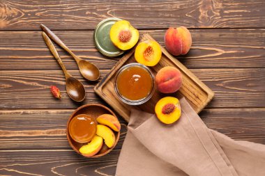 Şeftali reçeli kavanozu ve ahşap arka planda taze meyvelerle kompozisyon