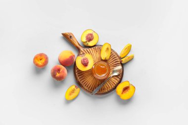 Ahşap tahta tahta, şeftali reçeli kavanozu ve arka planda taze meyveler.