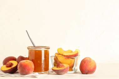 Tatlı şeftali reçelli kavanoz ve masada taze meyve.
