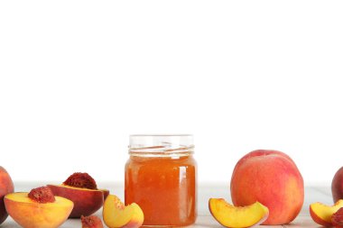 Tatlı şeftali reçelli kavanoz ve masada taze meyve.