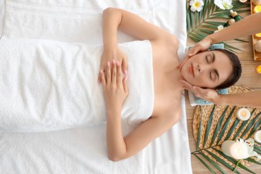 Kaplıca salonunda masaj yaptıran genç bir kadın.