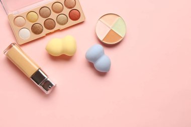 Pembe arka planda dekoratif kozmetik ve makyaj süngeri seti